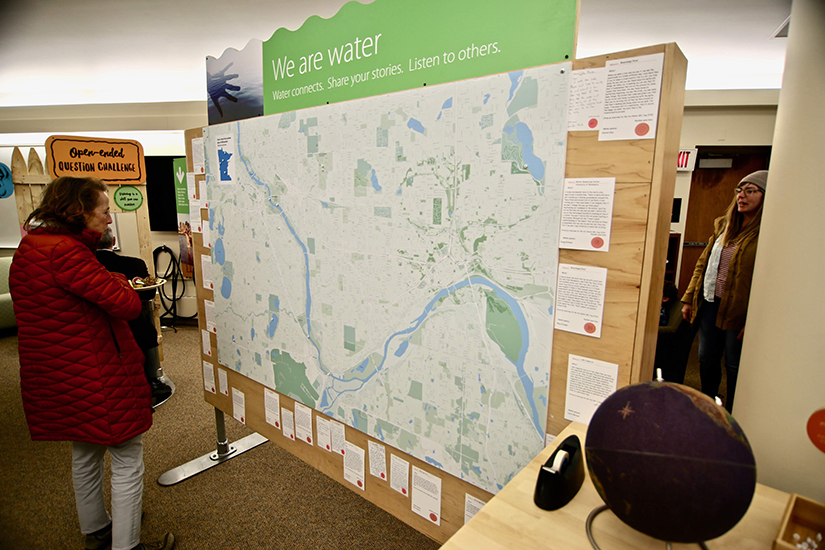 Visitors to We Are Water MN exhibit stop to examine a map