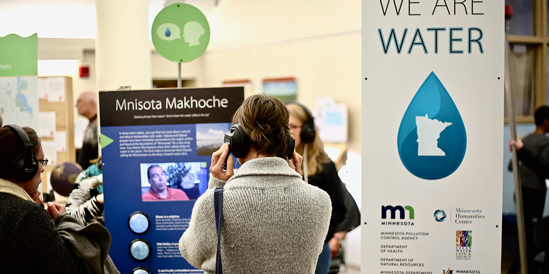 Two women stop to watch a video at the "We Are Water MN" traveling exhibit.