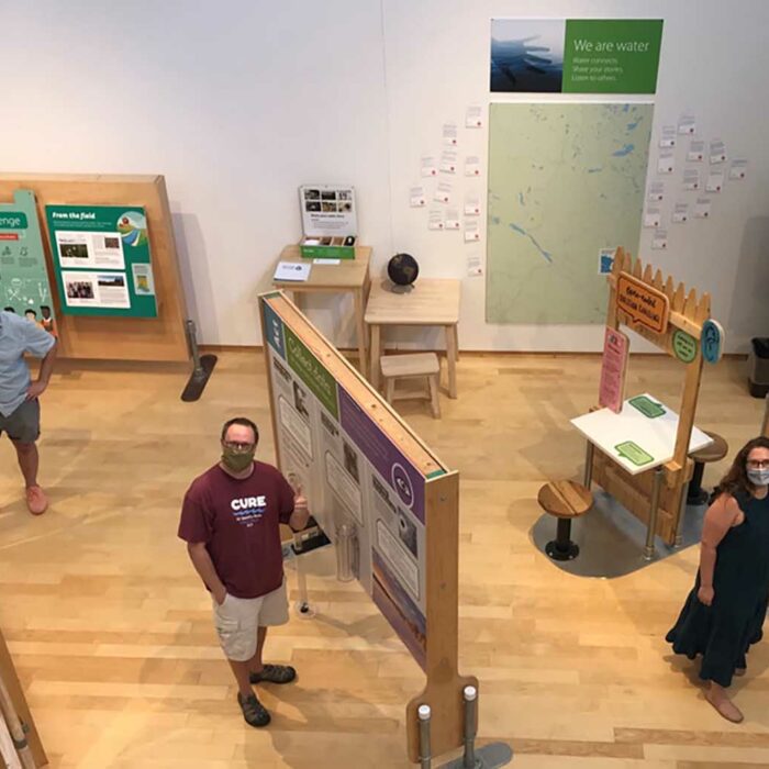 Volunteers stop working on installation of We Are Water MN traveling exhibit to take a photo.