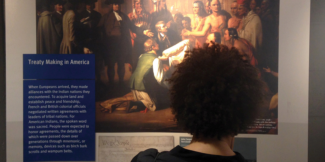 A visitor at the Why Treaties Matter traveling exhibit pauses to read a display on "Treaty Making in America."