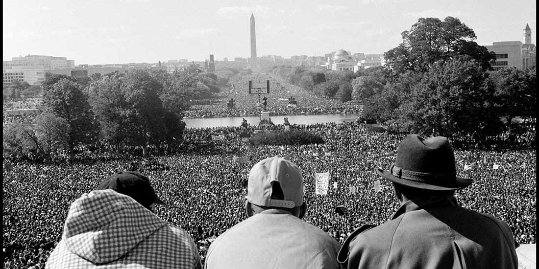 Three black men look on during the Million Man March on Washington, D.C.'s National Mall.